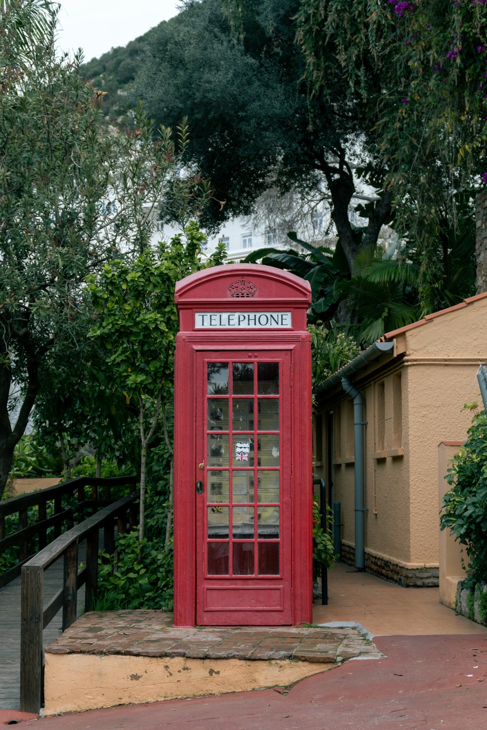 a red phone booth sitting on the side of a road