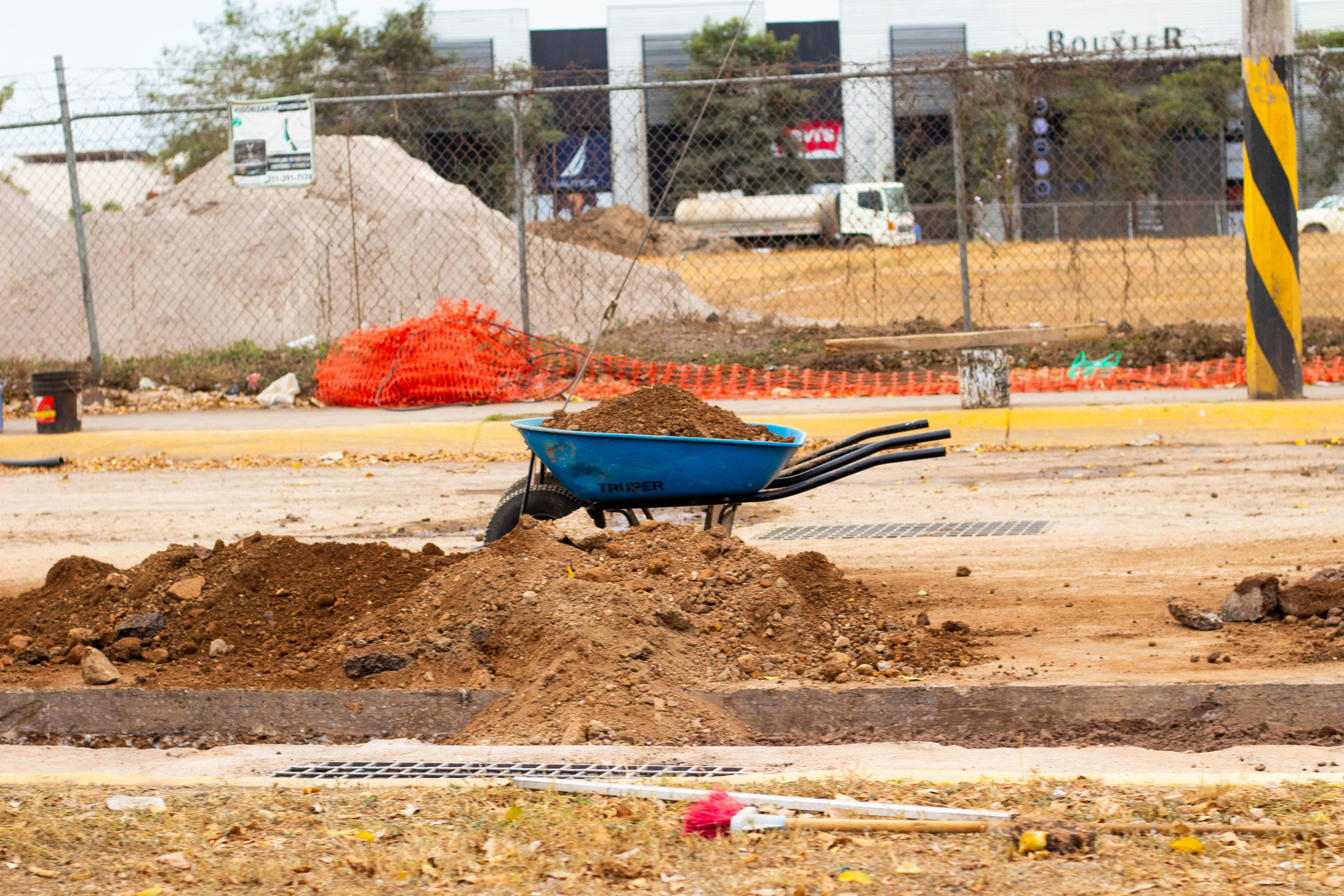 a blue wheelbarrow filled with dirt on a construction site