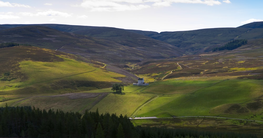 a scenic view of a valley with a house in the distance