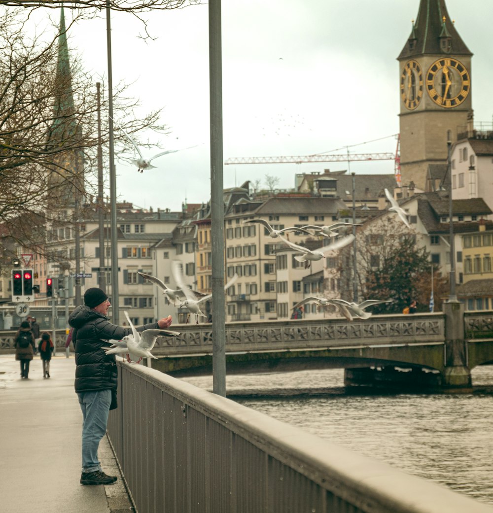 a man standing on a bridge next to a body of water