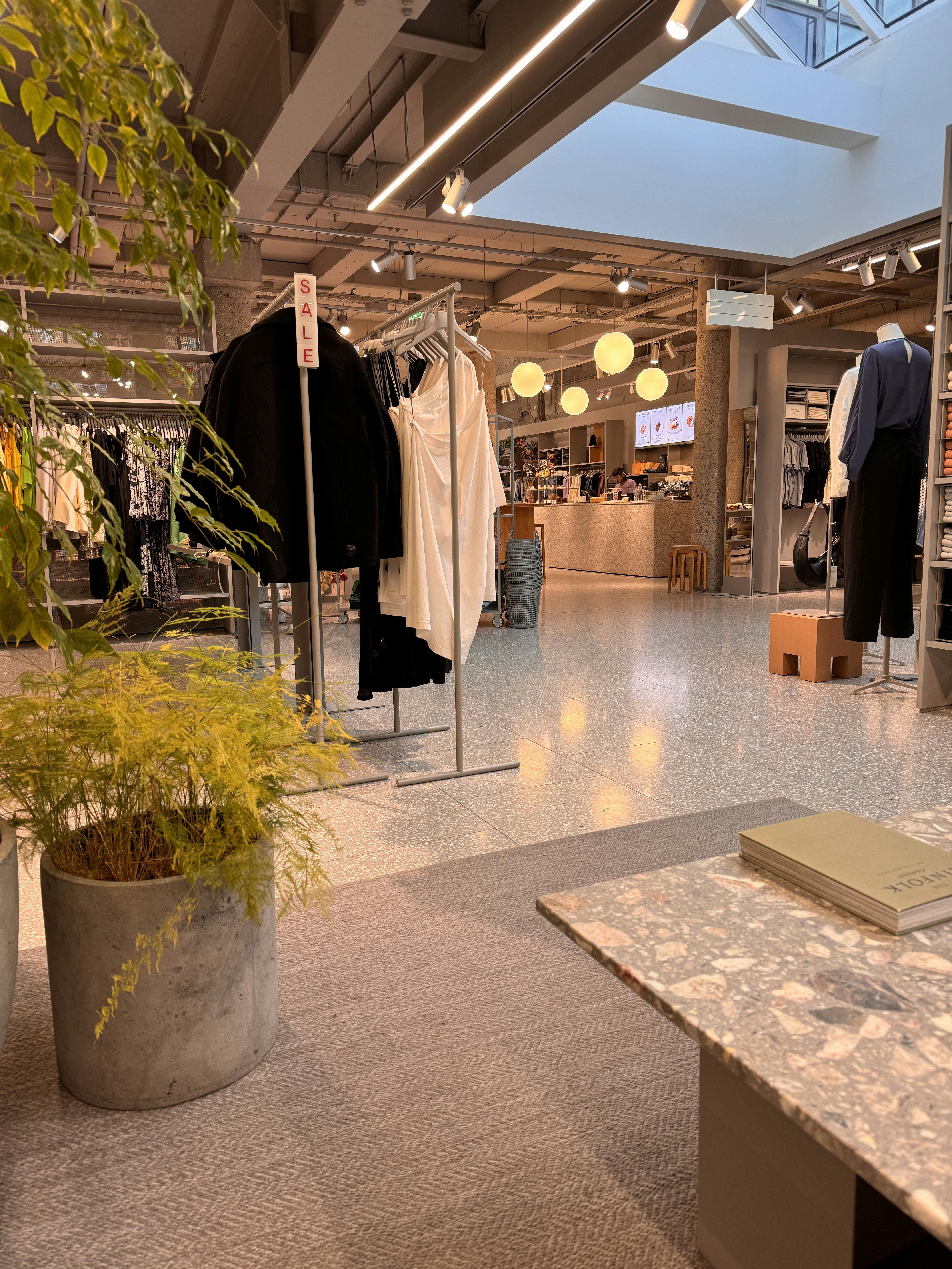 a clothing store with a plant in the middle of the room