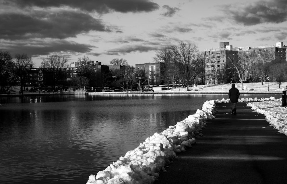 a man sitting on a bench next to a body of water