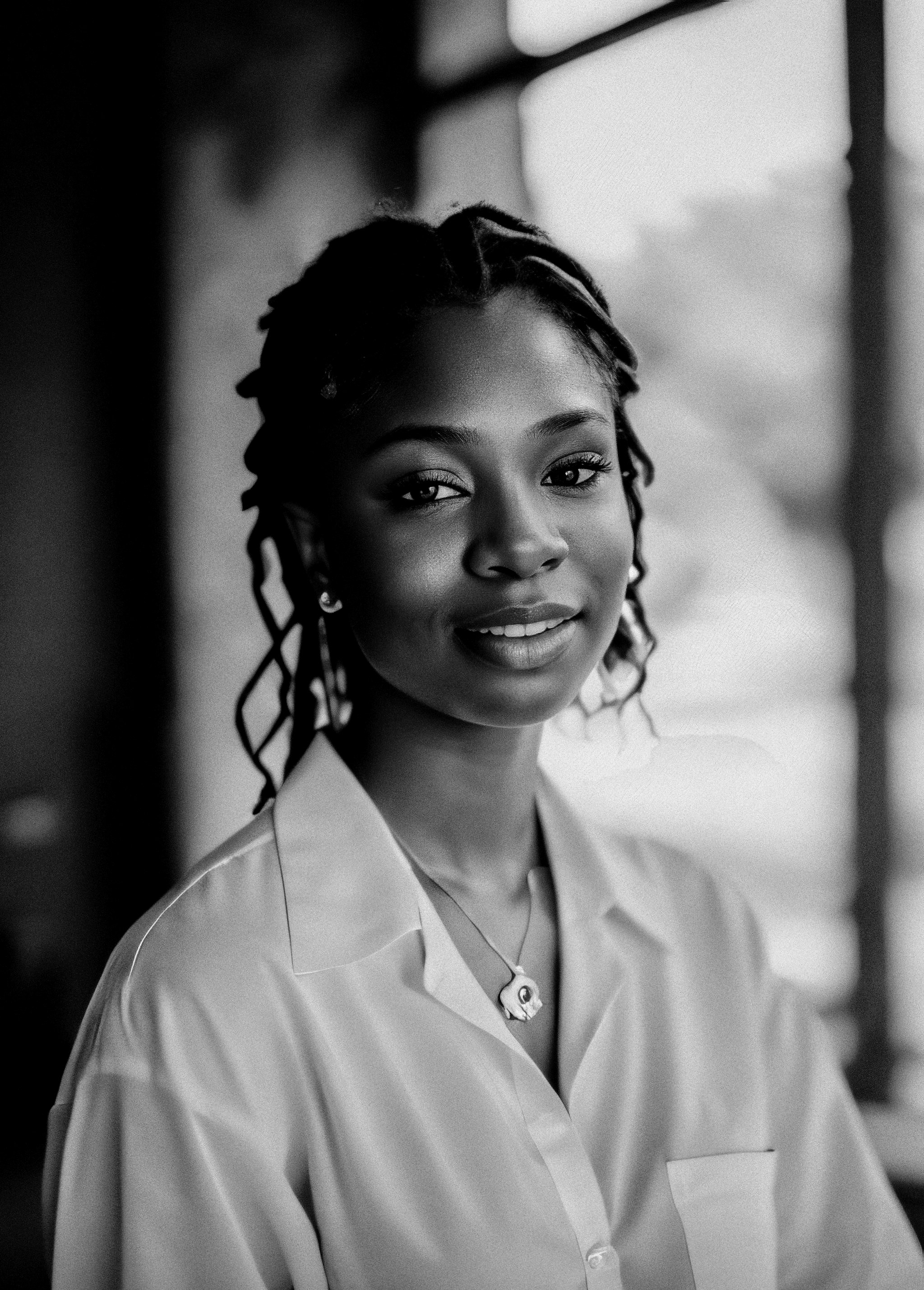 Portrait d'Amina Diallo, femme aux cheveux tressés avec un sourire chaleureux
