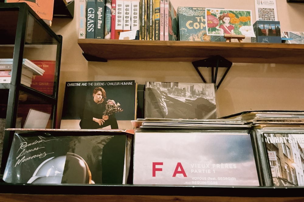 a shelf filled with cd's and books on top of a wooden shelf