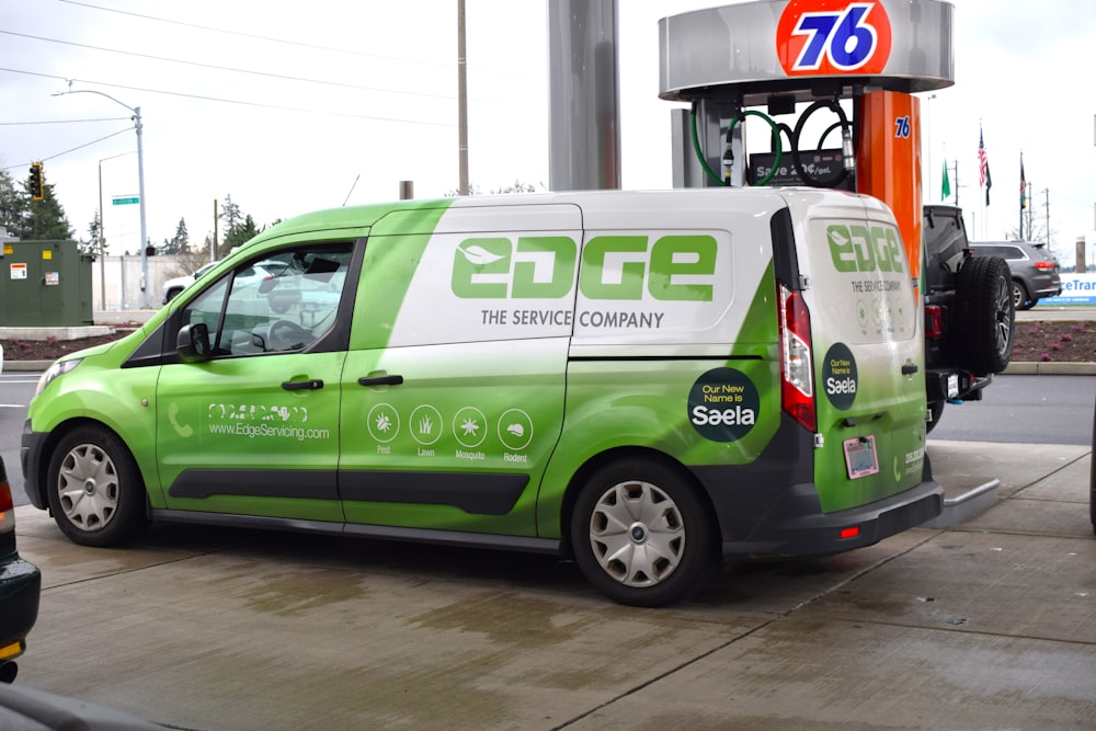 a green and white van parked in front of a gas station