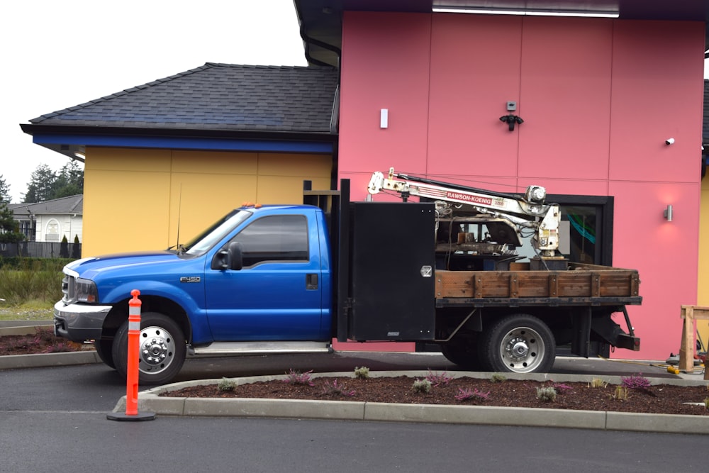 a blue truck parked in front of a pink building