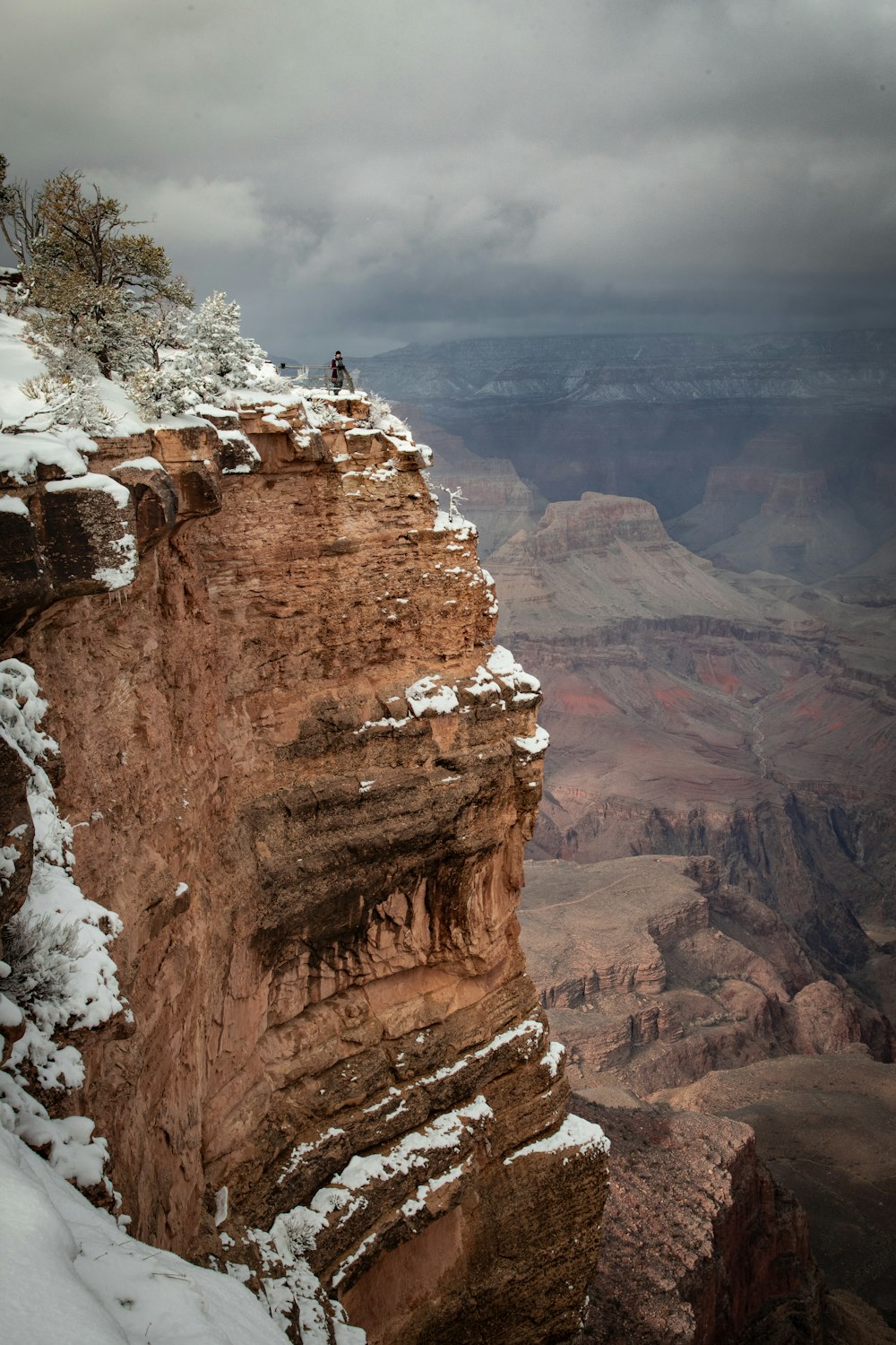 a man standing on top of a snow covered cliff