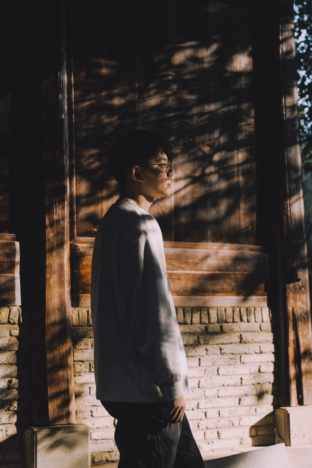 a man standing in front of a brick wall