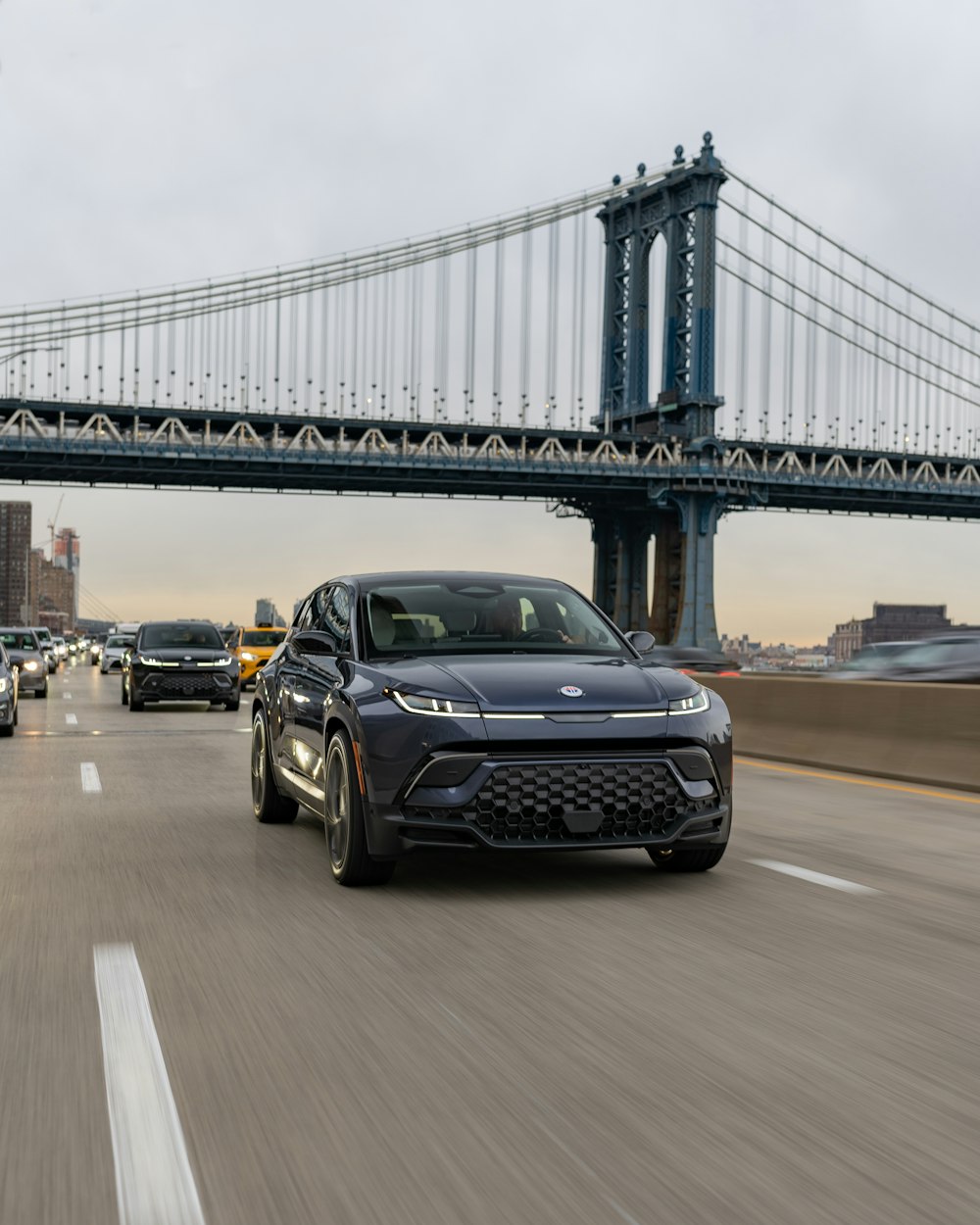 a black car driving down a highway next to a bridge