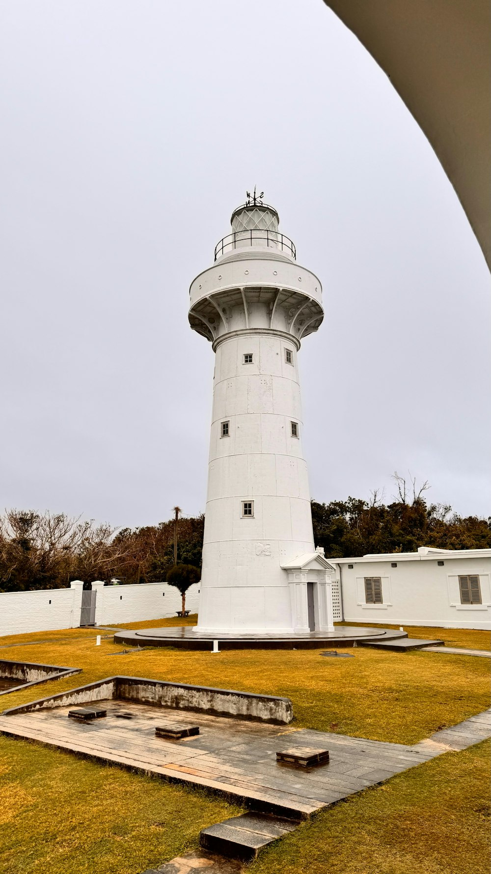 a white light house sitting on top of a lush green field