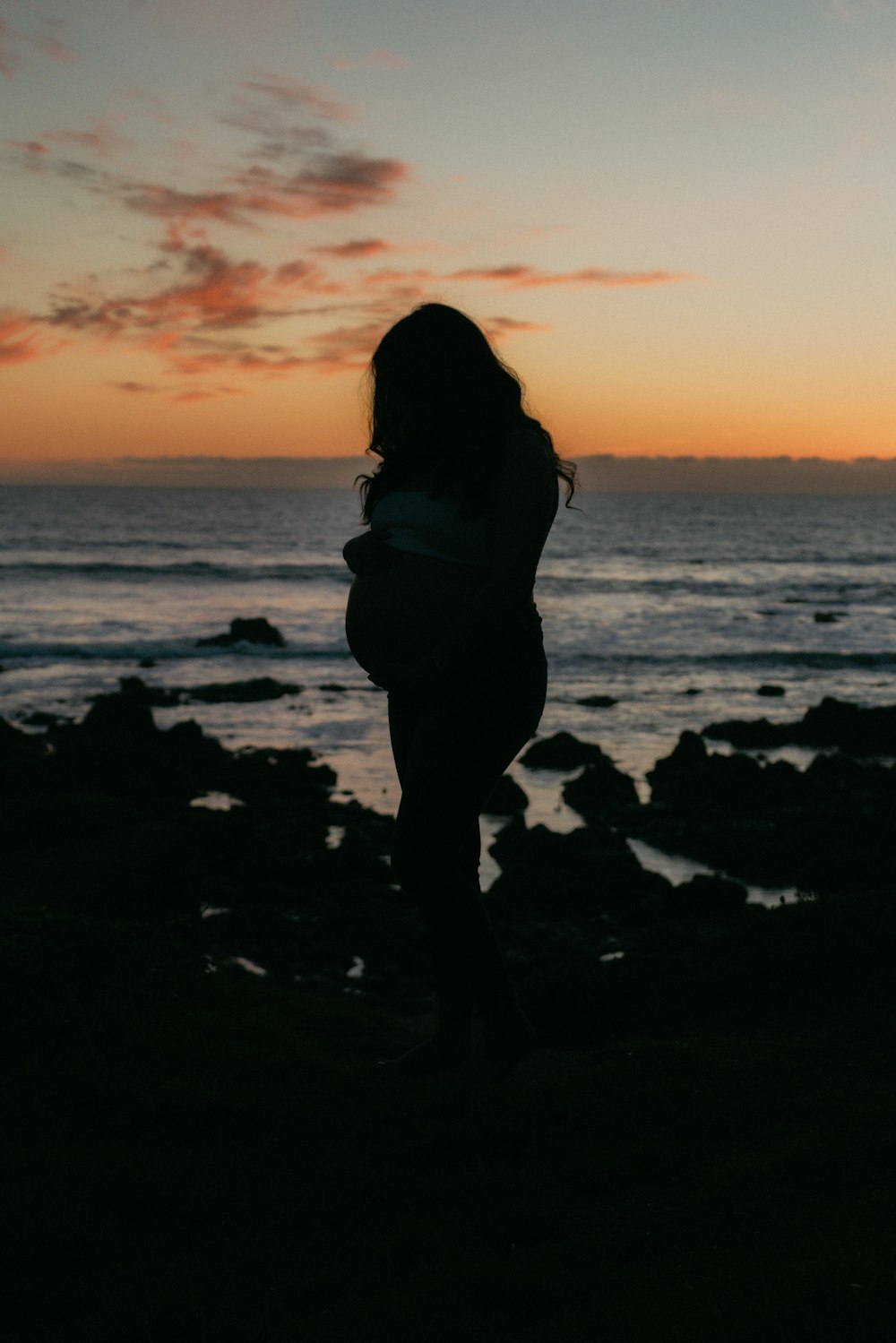 a woman standing on a beach at sunset