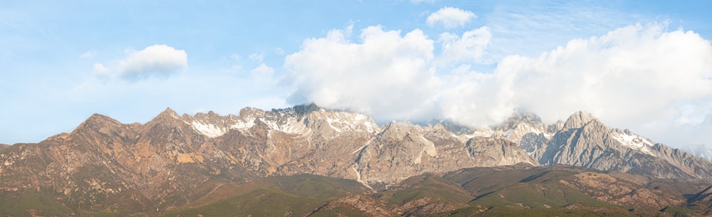 a mountain range with a few clouds in the sky