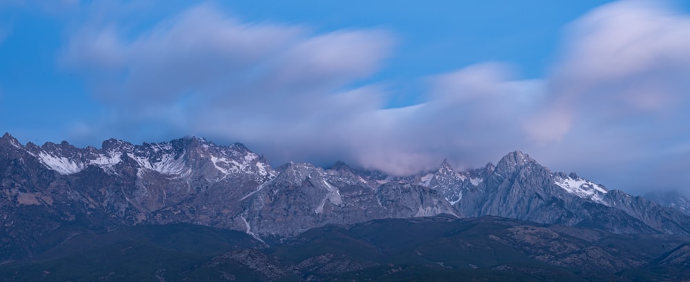 the mountains are covered in snow and clouds