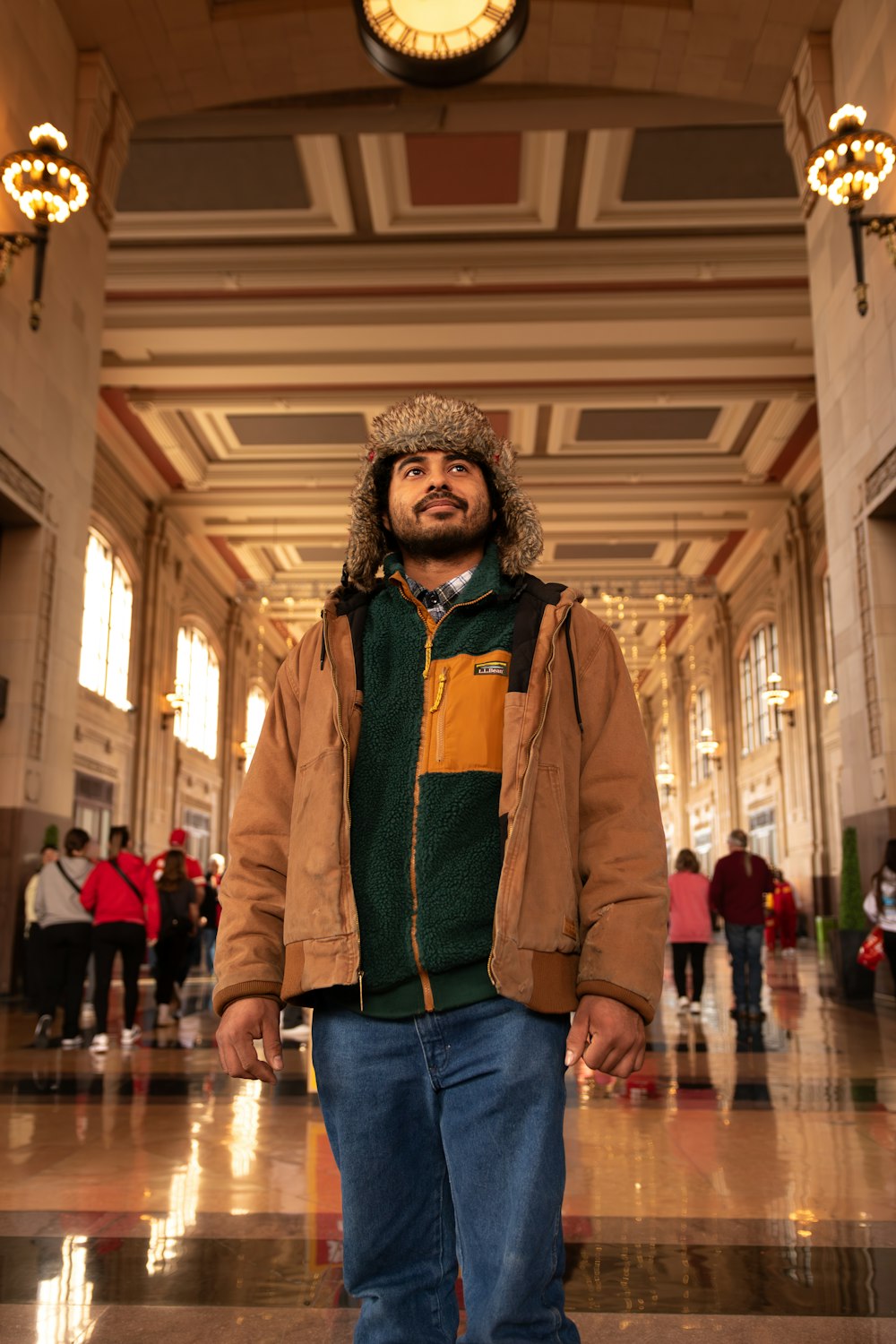 a man standing in a building with a clock above him