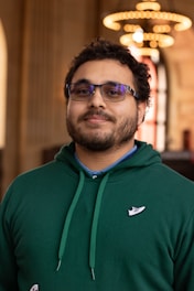 a man wearing a green sweatshirt and glasses