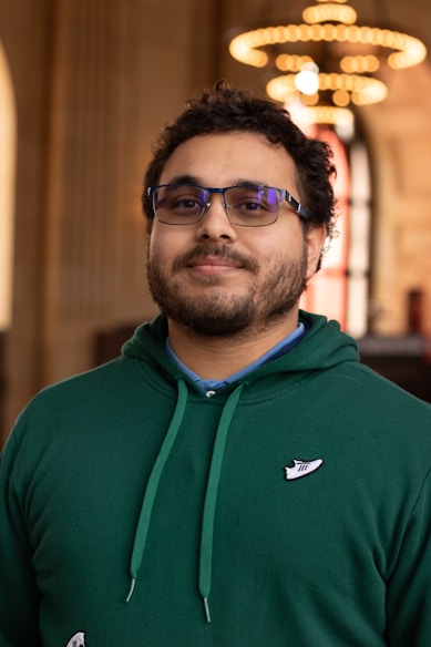 a man wearing a green sweatshirt and glasses
