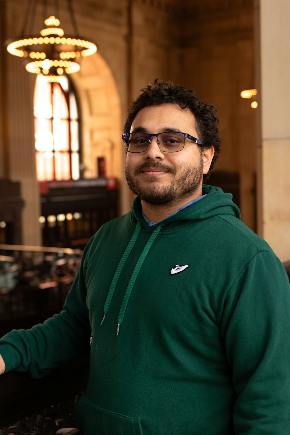 a man in a green hoodie standing in a building