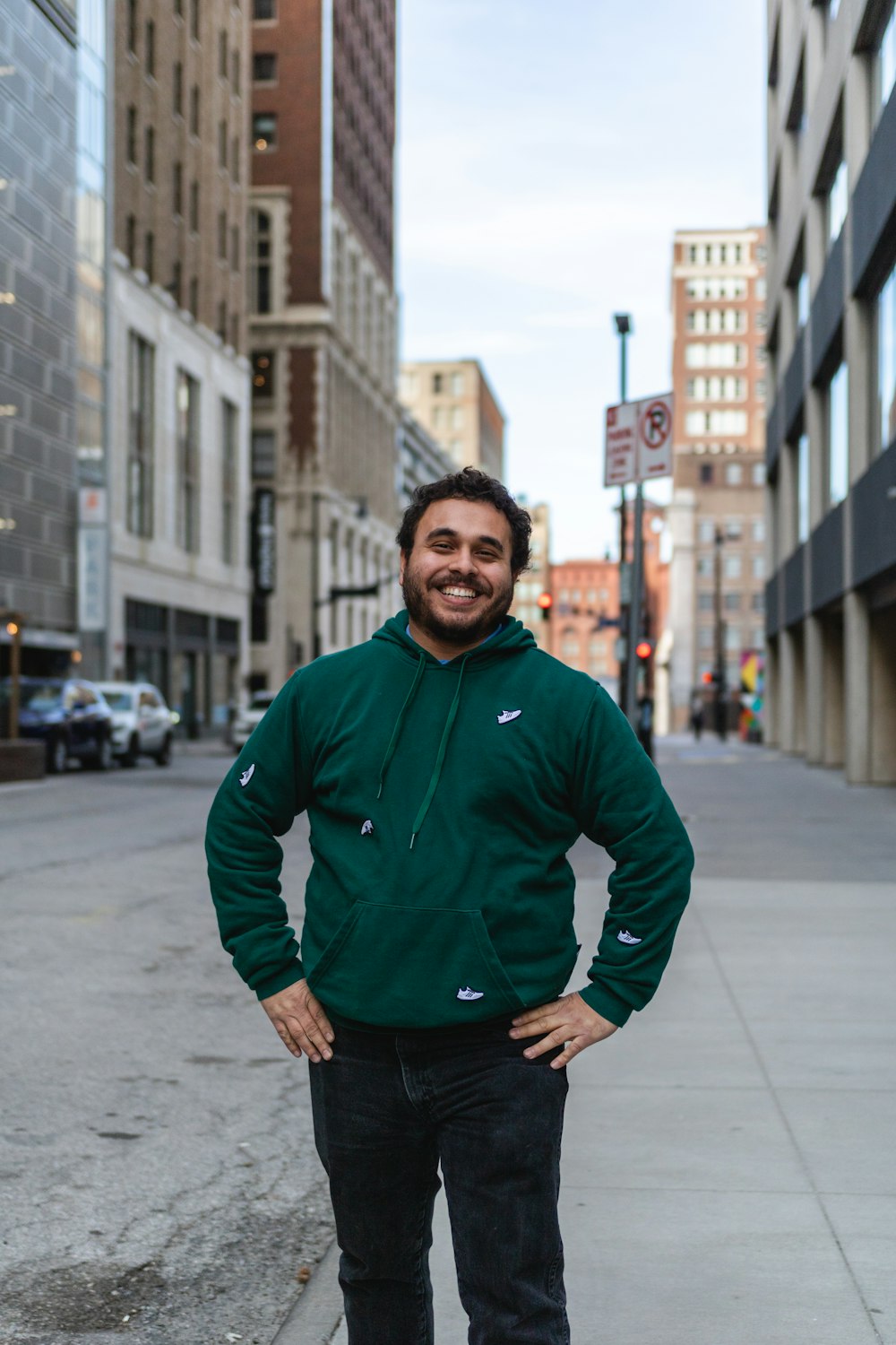 a man in a green jacket standing on a sidewalk