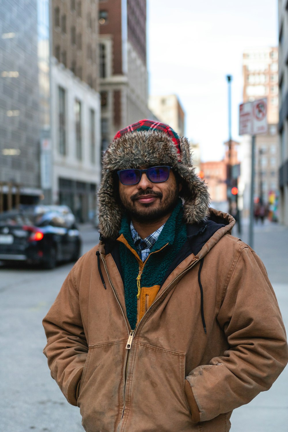 a man wearing a hat and jacket standing on a street