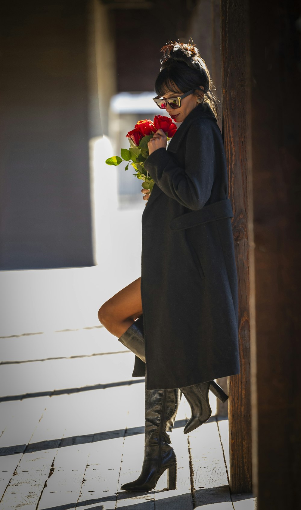 a woman in a black coat is holding flowers