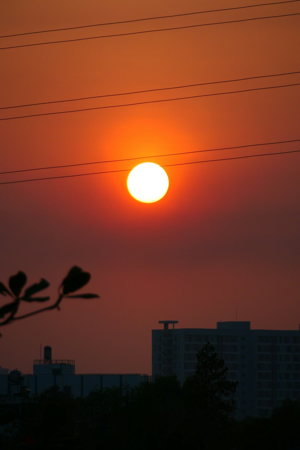 the sun is setting over a city with power lines