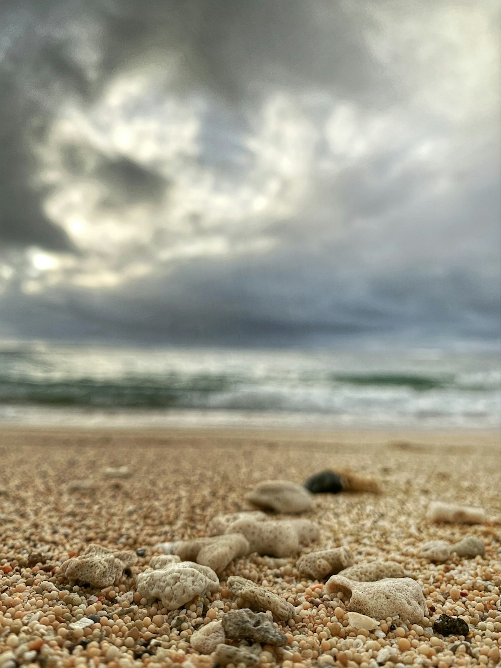 rocks and pebbles on a beach under a cloudy sky