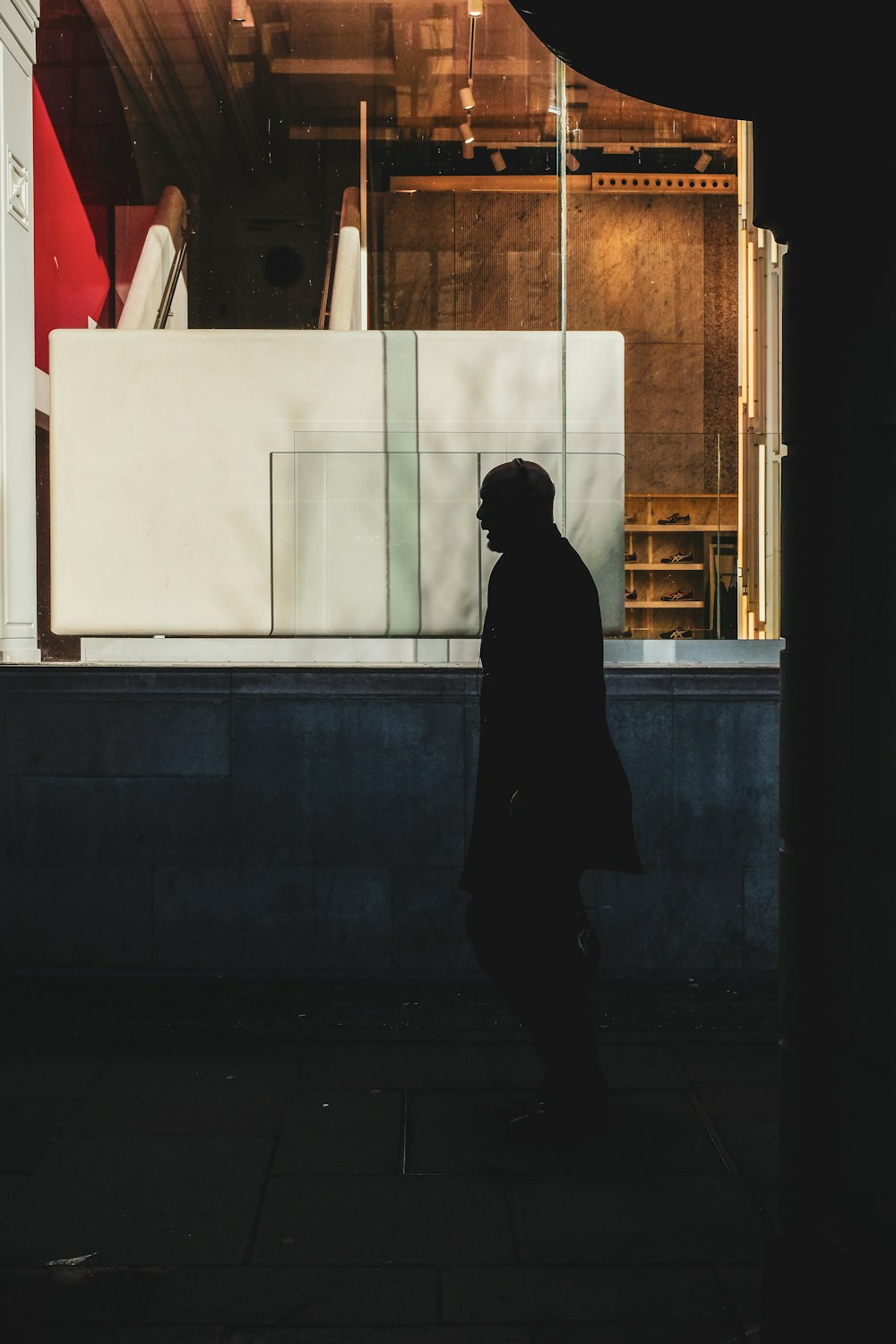 a man walking down a sidewalk next to a building