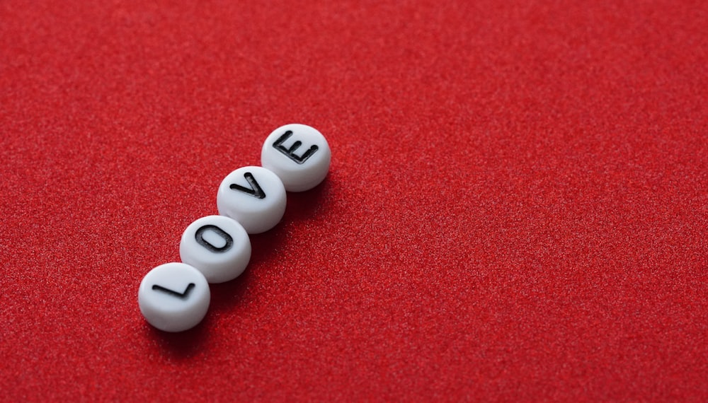 a row of love pills sitting on top of a red surface