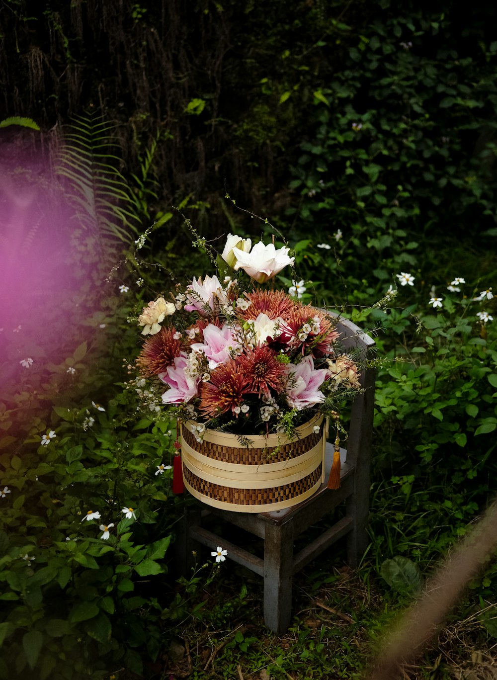 uma cesta de flores sentada em um banco de madeira