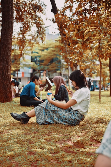 a group of people sitting on the ground in a park