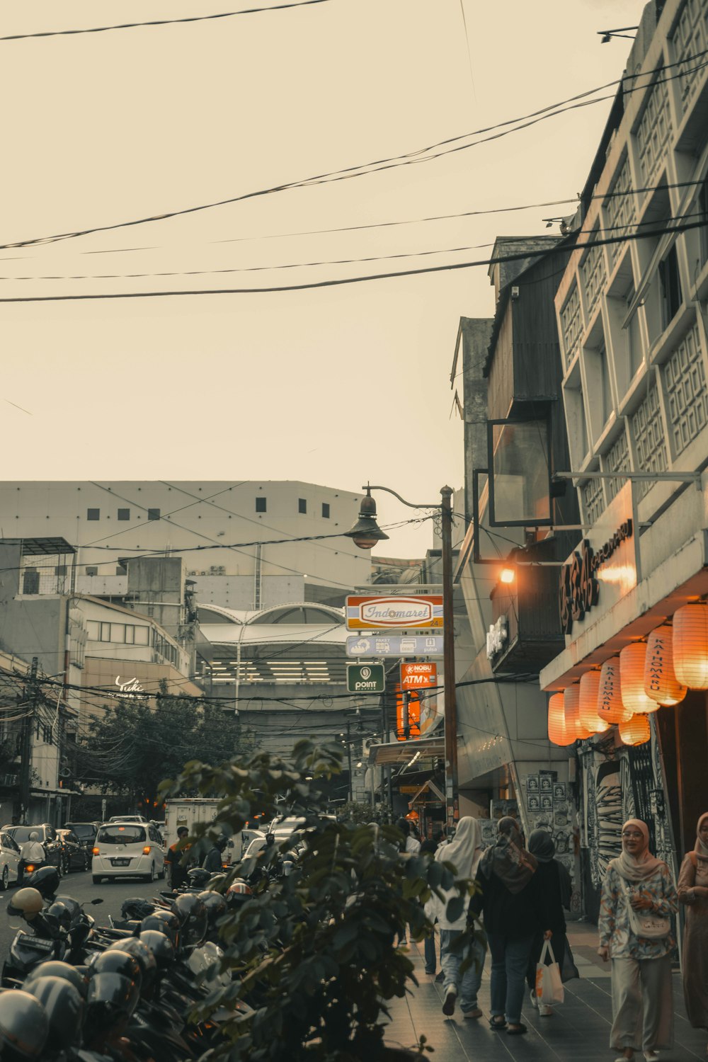 a group of people walking down a street next to tall buildings