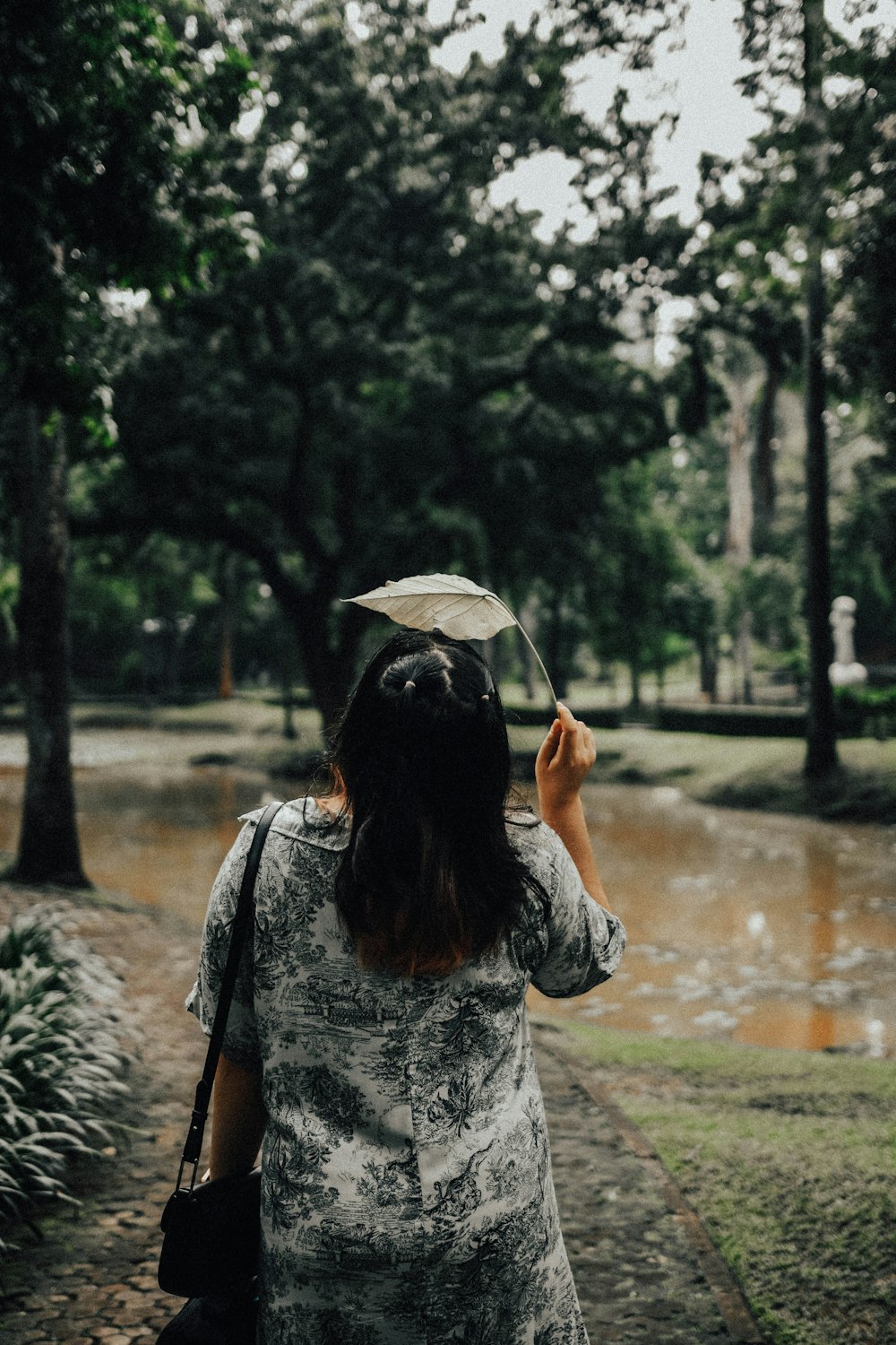 a woman standing in a park holding an umbrella