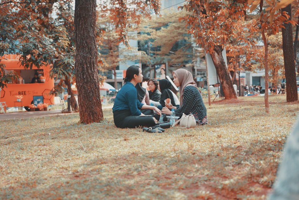 a group of people sitting on the ground in a park