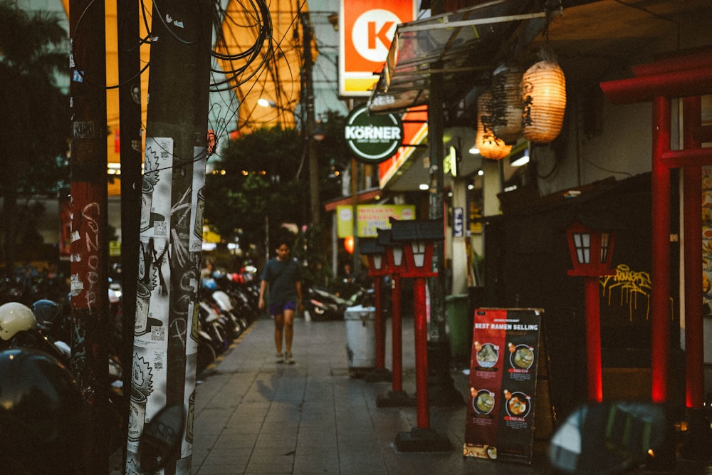 a woman walking down a street next to a row of parked motorcycles