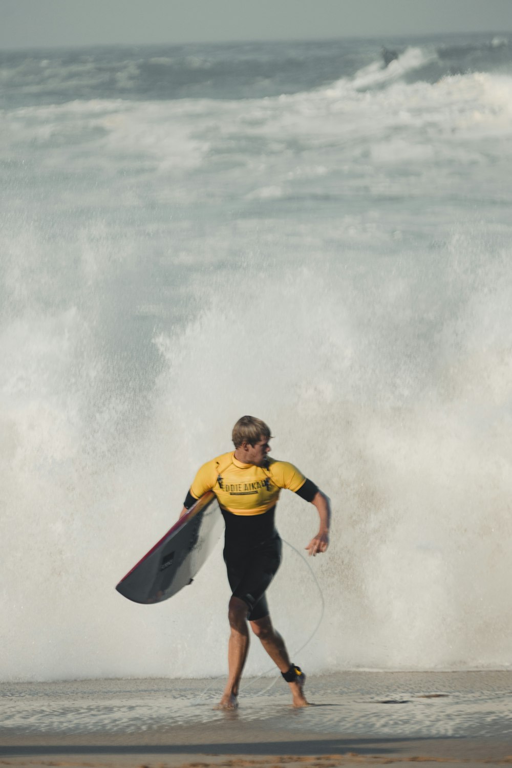 잠수복을 입은 남자가 서핑 보드를 들고 있습니다.