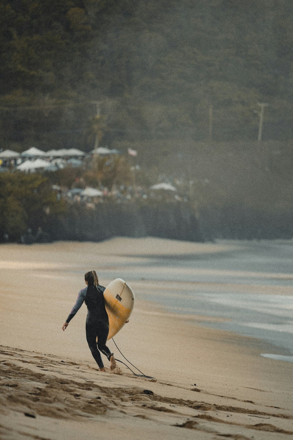 eine Person, die mit einem Surfbrett am Strand spazieren geht