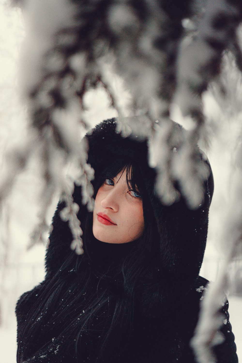a woman in a black coat is standing in the snow