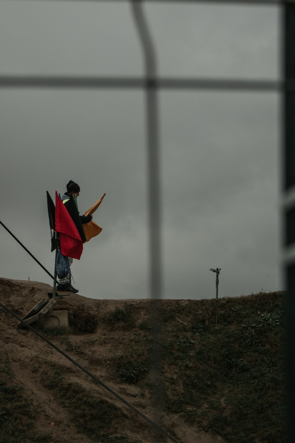 a man walking up a hill carrying a red flag