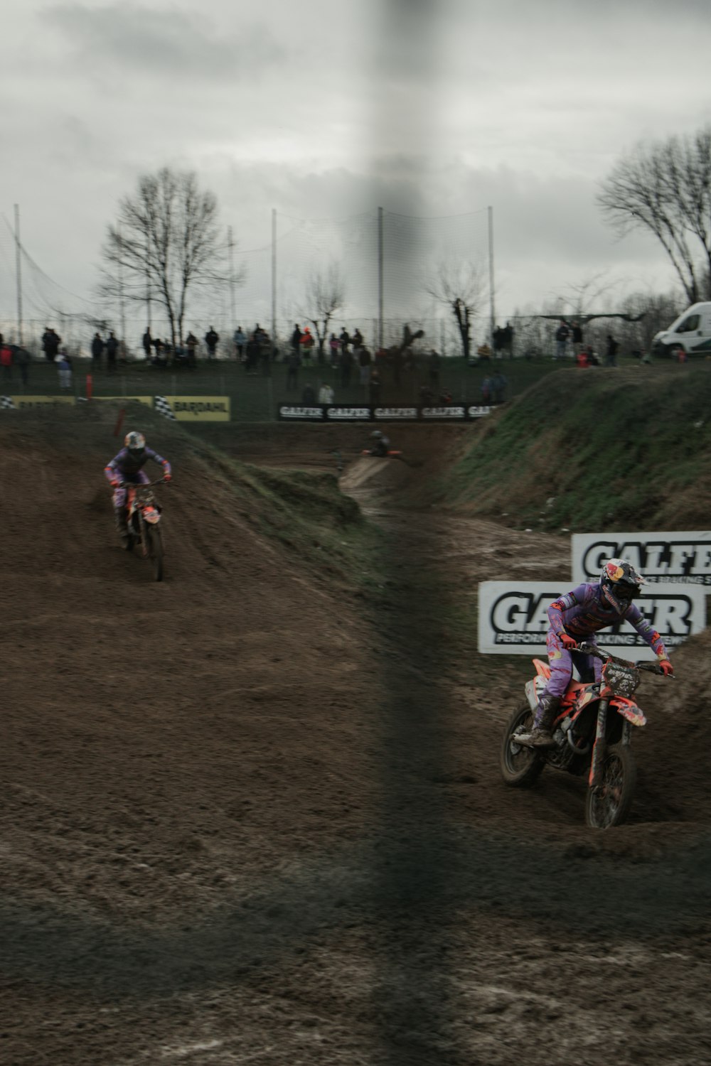 two people riding dirt bikes on a dirt track