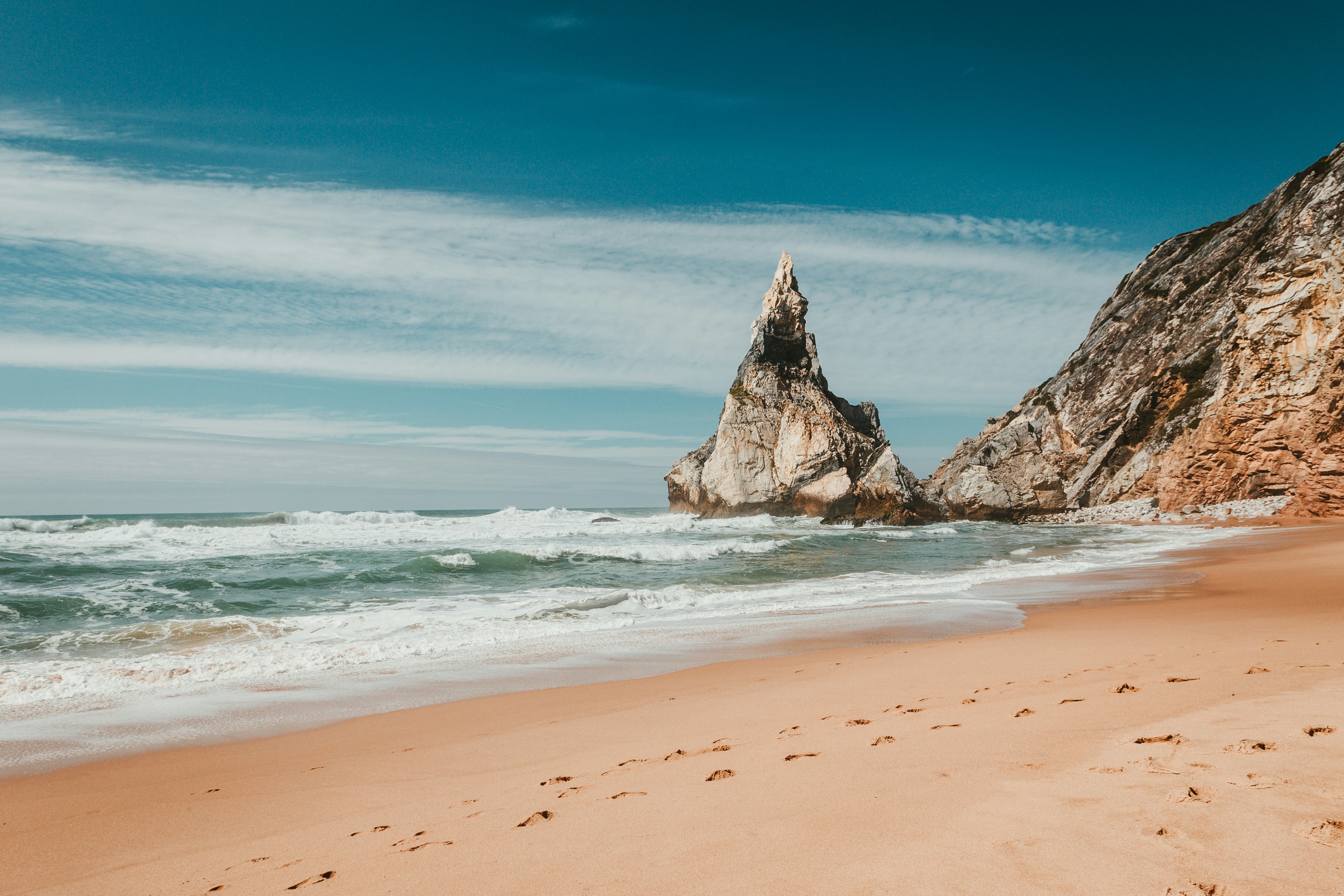 a rocky outcropping on a beach next to the ocean
