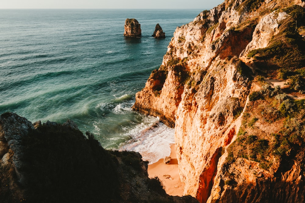 a rocky cliff overlooks the ocean and beach