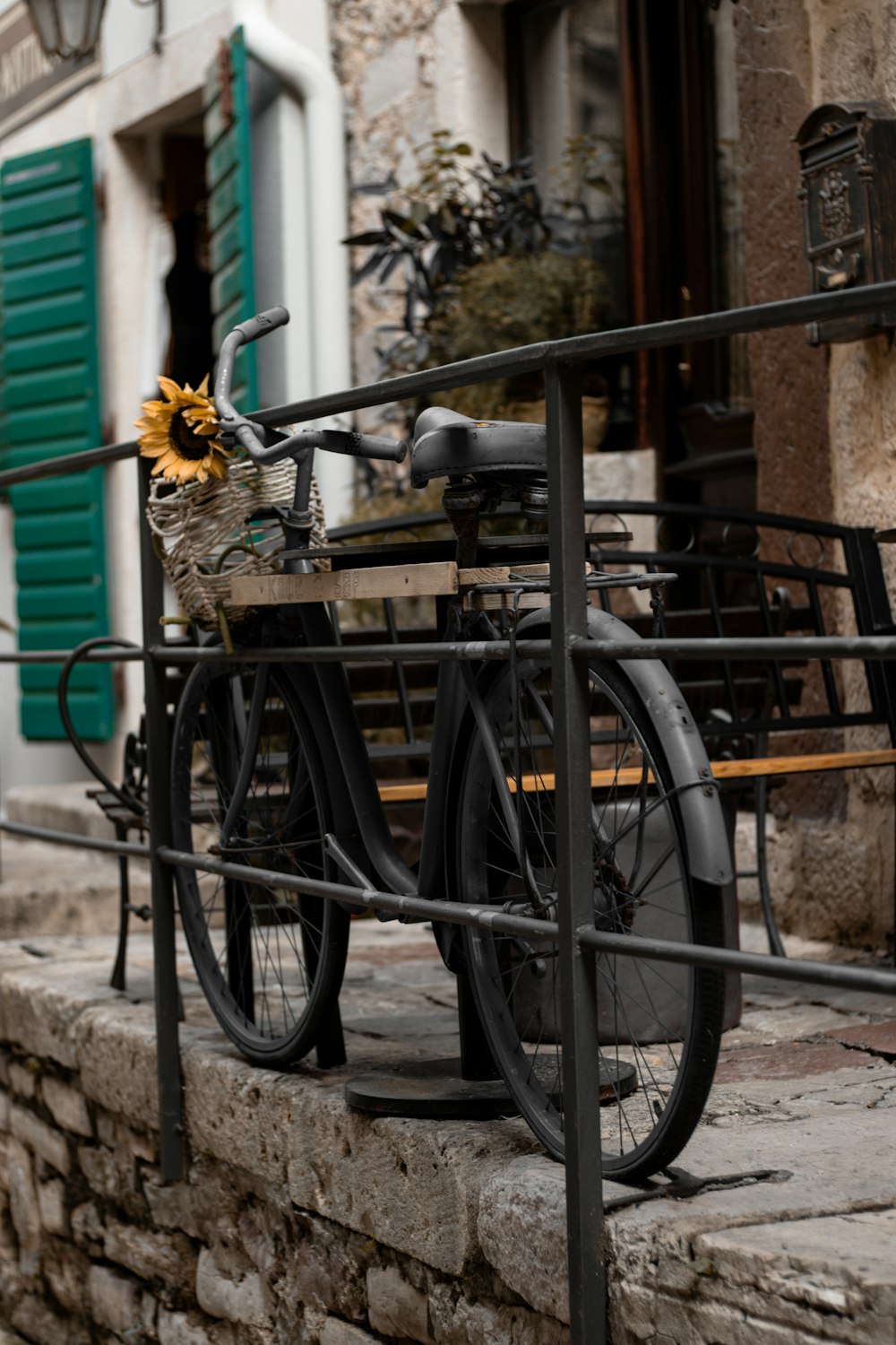 a bicycle parked next to a building with green shutters