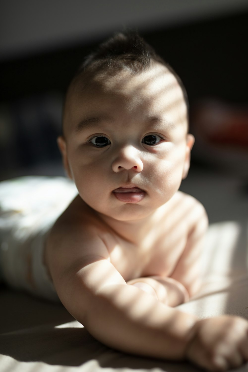 a baby laying on a bed looking at the camera