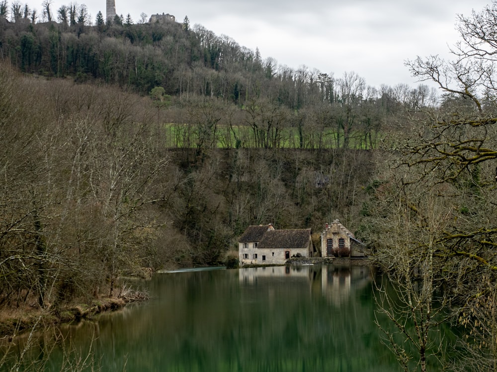 a house sitting on top of a lake surrounded by trees