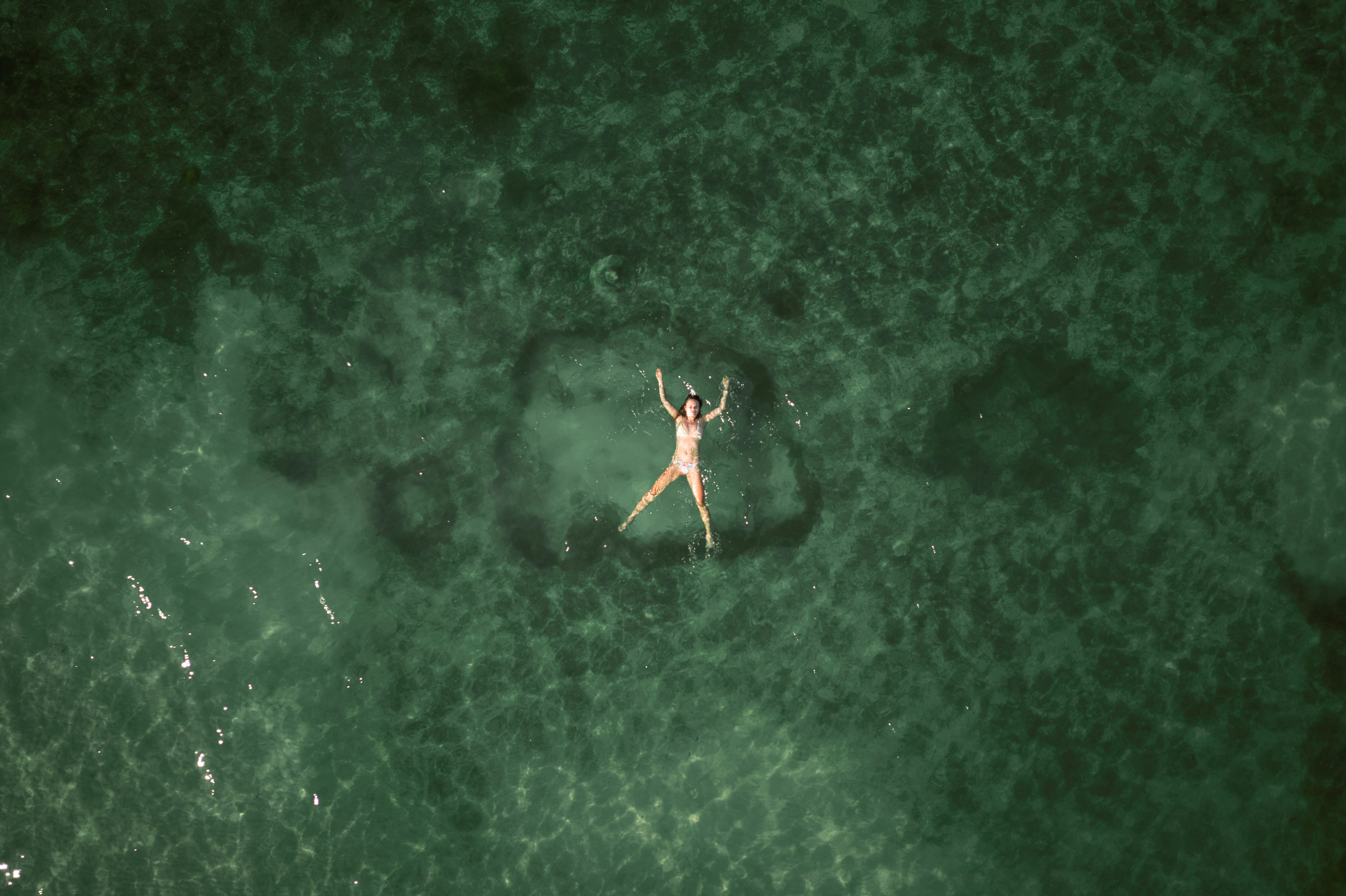 a person floating in the ocean on a surfboard, 