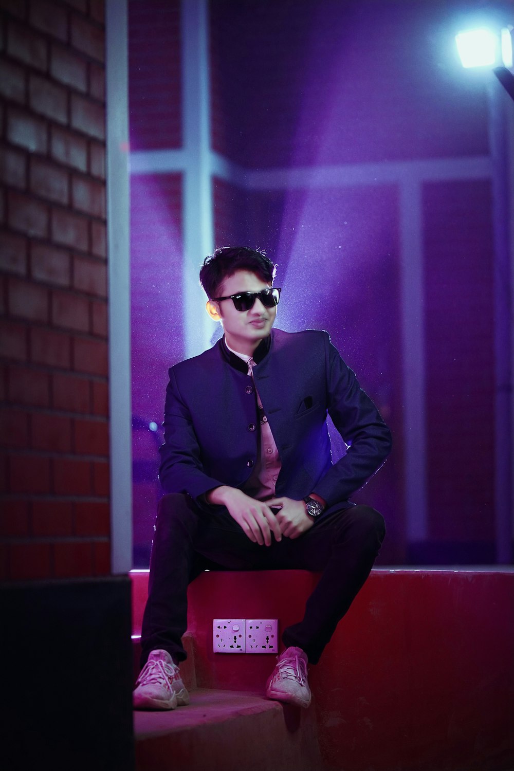 a man in a suit and sunglasses sitting on a step