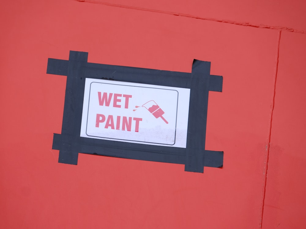a red wall with a sign that says wet paint