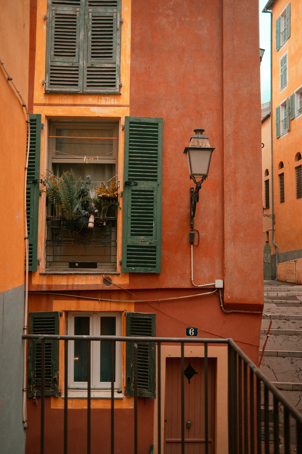 a building with green shutters and a lamp post