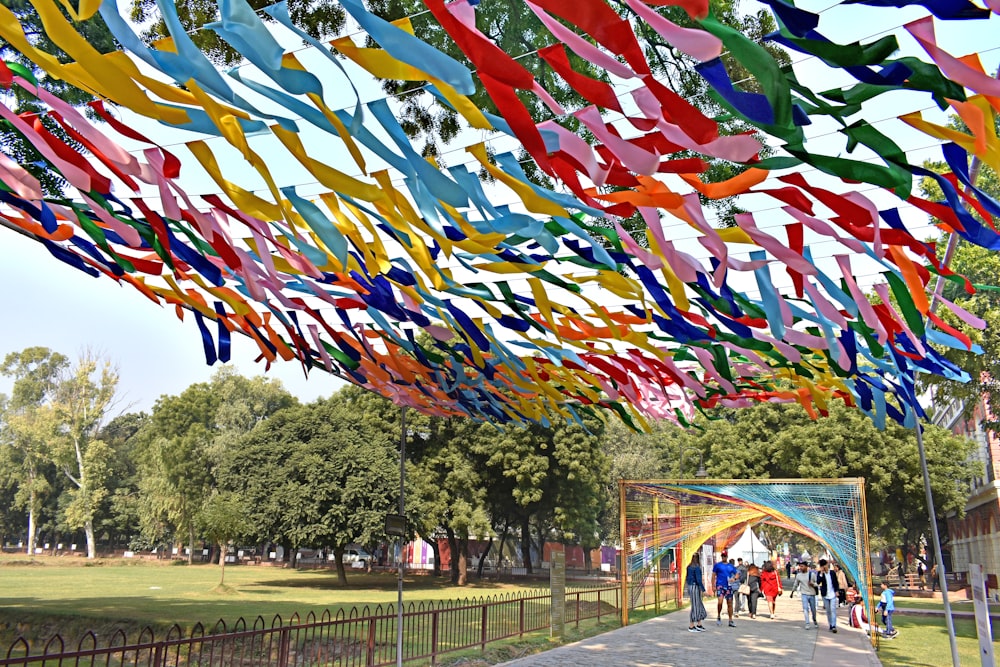 a bunch of colorful streamers hanging from the ceiling of a park