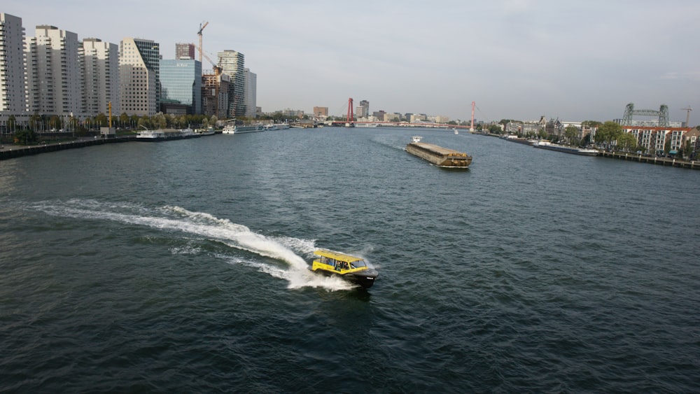 a yellow boat traveling down a river next to tall buildings